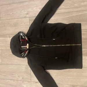 burberry korta - Säljer en svart hoodie med dragkedja och huva från burberry. Lite av dragkedjan har gått av men det märker man inte. Pris kan diskuteras! hör av er om frågor 