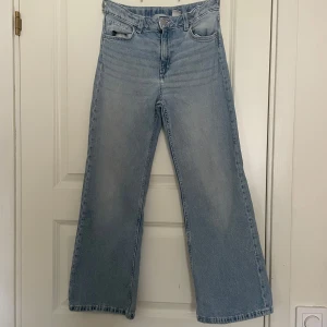 Ljusblå bagge bootcut jeans från H&M - Säljer ett par ljusblå bootcut jeans från H&M med justerbar midja. De har en baggy passform och klassisk femficksdesign. Perfekta för en avslappnad stil. Älskade dessa byxor men är tyvärr för små. Bra skick förutom att en av de som håller upp skärpet åkte av men jag sydde fast den så det går att använda normalt. Säljs inte mer.