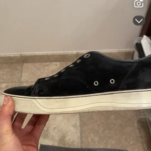 Svarta sneakers med vit sula - Säljer ett par svarta lanvin. Skorna har en klassisk design med en rund tå och är tillverkade i mocka. Dustbag medföljs 40-41