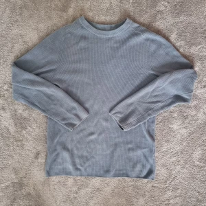 Blå stickad tröja från FSBN - Säljer en stilren blå stickad tröja från FSBN i slim fit. Tröjan har långa ärmar och en rund halsringning, perfekt för en avslappnad look. 