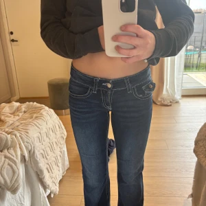 Mörkblå jeans med låg midja - Snygga mörkblå jeans med låg midja och vita sömmar. De har en klassisk femficksdesign och knappar på bakfickorna. Perfekta för en avslappnad stil.