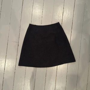 Grå/svart räflad stickad kjol i ull 🍒❣️ - Snygg grå/svart kjol i ull med en klassisk A-linjeform. Perfekt för kyligare dagar och lätt att matcha med olika toppar. Ett måste i garderoben för en stilren look.