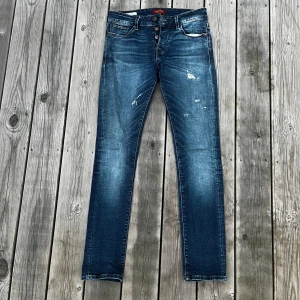 Blå jeans med slitningar - Blå jeans från Jack and Jones. De har en snygg tvätt och snygga slitningar. Strl: 28/30. Modell: Slim/Glenn. Mycket bra skick. Fråga vid funderingar.