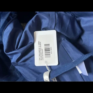 Marinblå långklänning - Elegant marinblå långklänning med glittrig tyllkjol och justerbara axelband. Perfekt för en festlig kväll med sin vackra passform och subtila glans. Klänningen har en dragkedja i ryggen för enkel påklädning. Säljer balklänningen då den inte passade:) 