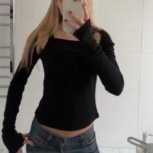 Svart offshoulder topp från NA-KD - Snygg svart cutout topp från NA-KD i storlek S. Toppen har långa ärmar och en stilren design. Använd en gång men så snygg!