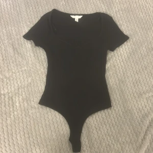 Svart ribbad bodysuit - Säljer en jätte snygg T-shirt body från H&M! Mycket bra skick och aldrig använd.💕