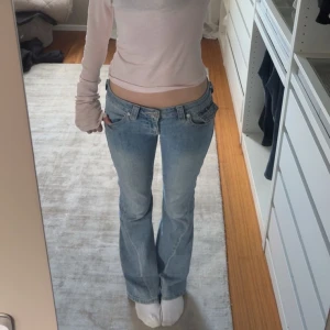 True Religion Jeans Joey - Snygga ljusblå bootcut jeans från True Religion. De har en klassisk femficksdesign med knappar och dragkedja framtill. Bakfickorna har dekorativa sömmar och knappar. Perfekta för en avslappnad stil.