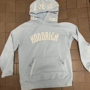 Ljusblå hoodie från Hoodrich - Säljer en ljusblå hoodie från Hoodrich med stor logga på framsidan och textdetaljer på huvan. Kan även medfölja en grå hoodrich tröja för priset 850 ( bilder privat för den gråa )