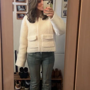 Vit stickad jacka/kofta - Säljer en mysig vit teddyjacka med långa ärmar och stora fickor framtill. Perfekt för kyliga dagar och ger en stilren look. Jackan har en normal passform och är superbekväm att bära. Passar perfekt till jeans eller klänning.