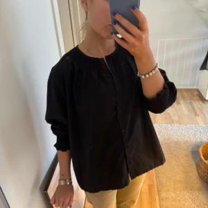 Svart blus med knappar, Isabell Marant - Snygg svart blus med knappar framtill och långa ärmar. Perfekt för en stilren look. Blusen har en rundad hals och en lös passform som ger en bekväm känsla. Inspirerad av Isabell marant 
