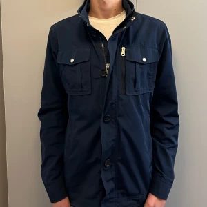 J.LINDBERG FIELDJACKET - Fet marinblå fieldjacka från J.Lindberg i storlek L (kan passa stor M) Jackan är i fint skick, inga defekter! Nypris runt 3500, skriv för fler funderingar 