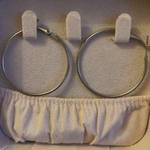 Säljer ett par stora, stilrena hoop-örhängen i silverfärg. Perfekta för att ge en elegant touch till din outfit. De är lätta och bekväma att bära hela dagen.