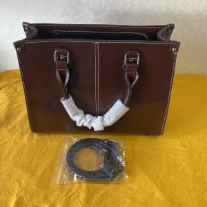 Brun skinnväska med dragkedja - Helt ny .( Äkta läder ) . Handväska Kvinnor Cross body Axella Äkta Läder Shopping Mode Kontor Kvinnlig Riktigt Kohud Messenger Top Handtag Väskor Snygg brun skinnväska med praktiska handtag och en avtagbar axelrem. Väskan har flera fack med dragkedja för enkel organisering. Perfekt för att bära dina dagliga nödvändigheter med stil.