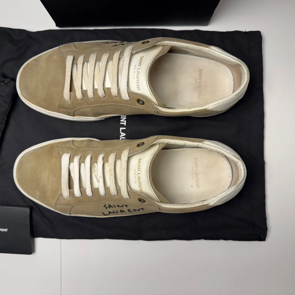 Snygga beige sneakers från Saint Laurent med vit sula och snörning. Skorna har en stilren design med Saint Laurent-logga på sidan. Perfekta för en avslappnad och trendig look. Inget og vid köp. Bara att höra av sig till oss vid minsta fundering😁 OBS Låda och dustbag kommer inte vid köp. Sulan är omfärgad till vit den är beige orginellt men om de tappar färg e de bara att färga de igen med solecolor . Kengät.