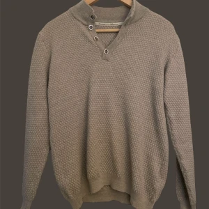 Stenströms  - Säljer en stilren beige stickad tröja med unikt mönster och knappar vid halsen. Perfekt för kyliga dagar och ger en avslappnad men ändå elegant look. Passar bra till både jeans och chinos.