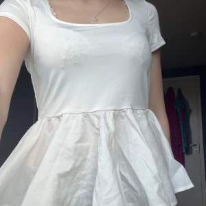 Vit kortärmad topp med öppen rygg - Säljer en söt vit topp med korta ärmar och en volangdetalj nedtill. Toppen har en öppen rygg med knytband som ger en fin detalj. Helt ny och aldrig använd! Storlek M men jag har vanligtvis xs och denna sitter bra 