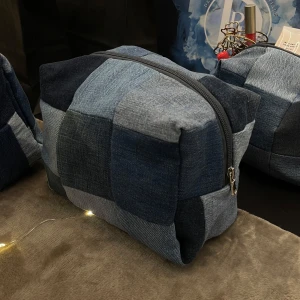 Handgjord patchwork necessär i återvunnet jeans - Snygg, rymlig, handgjord necessär i patchwork-stil gjord av olika nyanser av blått jeansmaterial som vi återvunnit. Den har en praktisk dragkedja upptill och är perfekt för att förvara smink eller andra artiklar. En unik accessoar för den som gillar denim!