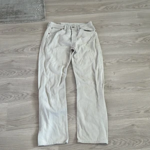 Beige Levis 501xx jeans - Säljer ett par klassiska beige Levis 501xx jeans. De har en rak passform och är tillverkade i bomull. Byxorna har den ikoniska Levis-lappen bak och en röd etikett på bakfickan.
