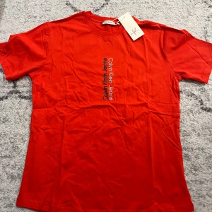 Röd t-shirt från Calvin Klein Jeans - Snygg röd t-shirt från Calvin Klein Jeans med tryck på framsidan. Perfekt för en casual look. Gjord i mjukt material för extra komfort. Passar S