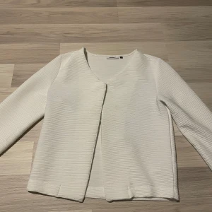 Vit ribbad kofta - Säljer en vit kofta. Den har en v-ringad design och långa ärmar. Perfekt för lager-på-lager och passar till många olika outfits. Obs, nopprig 