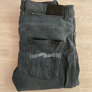 Nudie jeans - Säljer ett par snygga grå jeans från Nudie Jeans. De har en klassisk femficksdesign och en stilren broderad detalj på bakfickan. Perfekta för en avslappnad stil. Inga deffekter! Bara höra av sig vid eventuella funderingar!