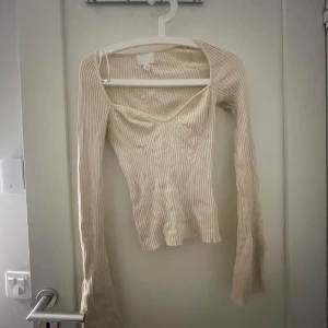 Beige ribbad topp från H&M - Säljer en stilren beige ribbad topp från H&M med v-ringning och långa ärmar. Perfekt för en chic och avslappnad look. Andvänt cirka 5 gånger max 