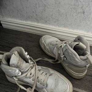 Vita sneakers - Säljer ett par vita sneakers med snörning. De har en klassisk design med rund tå och är perfekta för vardagsbruk.
