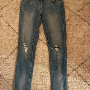 Blå jeans från Levi's - Snygga blå Levi's jeans i modellen Low Skinny 531. De har en låg midja och skinny passform med slitna detaljer på benen för en trendig look. Perfekta för en avslappnad stil. Storlek M. 