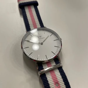 Randig klocka från Daniel Wellington - Snygg klocka från Daniel Wellington med en tidlös design. Klockan har en silverfärgad boett och minimalistisk design💓låda finns med