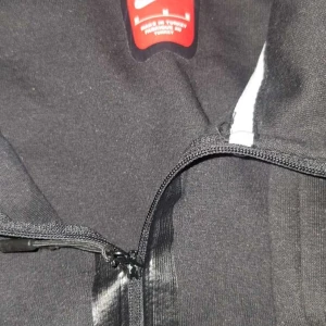 Svart Nike vindjacka med half zip - Svart vindjacka från Nike med diskret logga på bröstet och praktisk half zip-dragkedja. Jackan har en sportig look och är tillverkad i lätt polyester, perfekt för dig som gillar en clean och enkel stil.
