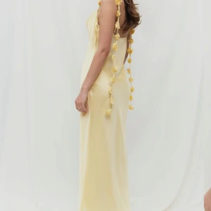 Ljusgul långklänning med blommiga band Gina tricot  - Superfin långklänning i ljusgul satin med smala axelband dekorerade med små blommor. Endast provad, prislapp kvar på. Storlek 38. Nypris 700