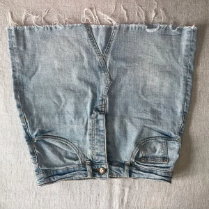 Ljusblå jeanskjol med rå kant - Ljusblå jeanskjol från Gina tricot med fransig kant och som fickor fram och bak. 