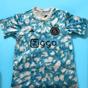 Ajax blåvit fotbollströja Adidas S - (Kom privat innan köp)Ajax fotbollströja från Adidas i slim fit med blått och vitt camouflage-mönster. Tröjan har korta ärmar, rund halsringning och klubbmärke samt Ziggo-logga på bröstet. Tillverkad i lätt och ventilerande polyester, perfekt för träning eller match.