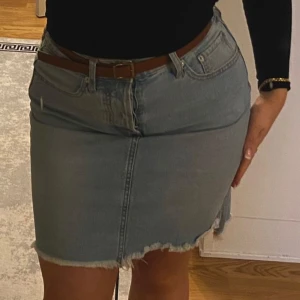 NY Ljusblå jeanskjol med fransad kant - Säljer en ljusblå jeanskjol med fransad nederkant och slits fram. Kjolen har klassiska fem fickor och bälteshällor. Perfekt för dig som gillar en avslappnad och trendig stil. Passar S  riktigt fin!!