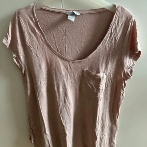 Puderrosa oversized t-shirt med ficka - Puderrosa t-shirt med kort ärm och rund halsringning. T-shirten har en liten bröstficka och är tillverkad i ett tunt, mjukt tyg. Perfekt för en chill och avslappnad stil