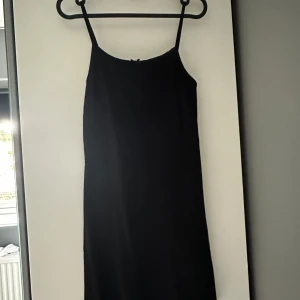 Svart ribbad klänning  - Svart ribbad kortklänning från Miss Selfridge med smala axelband och liten rosett vid urringningen. Klänningen har en enkel, rak passform och ärmlös design som känns både stilren och söt.