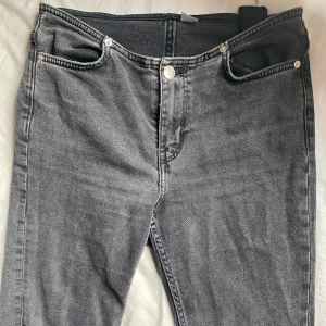 Grå jeans med bootcut  - Säljer ett par grå jeans med klassisk femficksdesign och bootcut  passform. Jeansen har en snygg tvättad look och silverfärgade knappar. Perfekta för dig som gillar en enkel och stilren vibe.