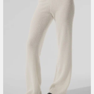 ALO Yoga Cashmere High-Waist Plush Waffle Pants in Ivory - Supermjuk och chunky vita mjukis från Alo Yoga med snyggt stickat mönster. Stilren design med diskret Alo-logga. Passar dig som gillar minimalistisk och cozy vibe. Lite korta i benen så passar en kortare person!  De var storlek S innan en tvätt men skulle säga passar en kort XS/S. Nypris 4350kr. 