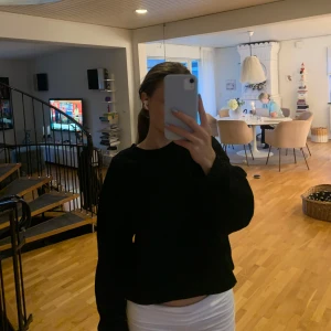 Svart croppad sweatshirt - En svart, croppad sweatshirt med rund hals och långa ärmar. Enkel och stilren modell som passar perfekt till jeans eller kjol. Mjuk och skön, perfekt för chill dagar eller när du vill ha en clean look.