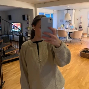 Beige stickad half zip tröja - Supermysig beige stickad tröja med half zip och ringdetalj på dragkedjan. Tröjan har långärmade, lite puffiga ärmar och ribbade muddar. Perfekt för lager-på-lager och chill dagar.