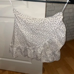 Vit prickig omlottkjol med volang - Superfin vit kortkjol med svarta prickar och omlottmodell💗