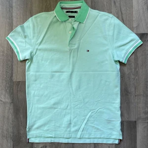 Tommy Hilfiger mintgrön piké - Fräsch mintgrön pikétröja från Tommy Hilfiger i storlek S. Regular fit plus denna är helt ny och oanvänd. Modellen är 167/63 