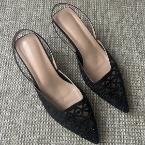 Svarta spetsiga slingback-pumps med pärlor - Eleganta svarta pumps med spetsig tå och liten klack. Skorna har transparent mesh med broderade detaljer och små svarta pärlor som ger en glittrig effekt. Slingback-modell med öppen häl och smal rem. Perfekta för dig som gillar en chic och trendig look. ALDRIG använda! 