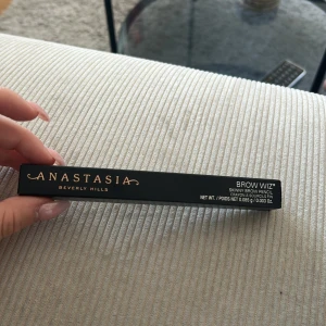 Anastasia Brow Wiz Medium Brown - Anastasia Beverly Hills Brow Wiz i färgen Medium Brown. En smal ögonbrynspenna som ger naturligt definierade bryn. Perfekt för att fylla i och forma brynen med precision. Kommer i en svart förpackning och är enkel att använda för ett snyggt resultat. Den är helt ny!