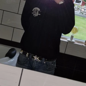 Äkta lukamachain bälte - Coolt svart bälte med glittrande stjärnformad spänne och nitar längs hela remmen. Perfekt för att ge en edgy touch till din outfit.