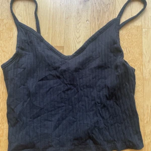 Svart ribbad linnetopp - Svart ribbad linnetopp från H&M Divided med smala axelband och v-ringning. Super bekväm och passar bra nu i varmt väder!