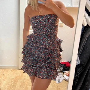 Söt klänning  - En jättesöt bandeau-klänning med volanger. Använd en del men i fint skick. Slutar vid mitten på låren på mig som är cirka 160cm