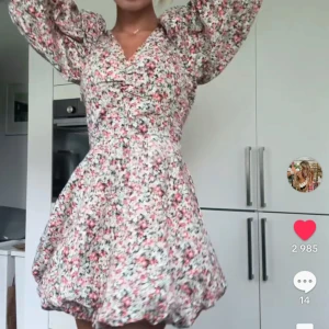 Blommig kortklänning med puffärmar - Supersöt kortklänning med blommigt mönster i rosa, vitt och grönt. Klänningen har v-ringning, volangdetaljer och långa puffärmar som ger en romantisk vibe. Perfekt för sommarens alla tillfällen!