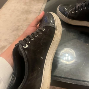 Lanvins  - Säljer ett par svarta sneakers med vit sula och svarta skosnören. Skorna har rund tå och platt sula, perfekt för en avslappnad stil. Passar till jeans eller andra vardagskläder.