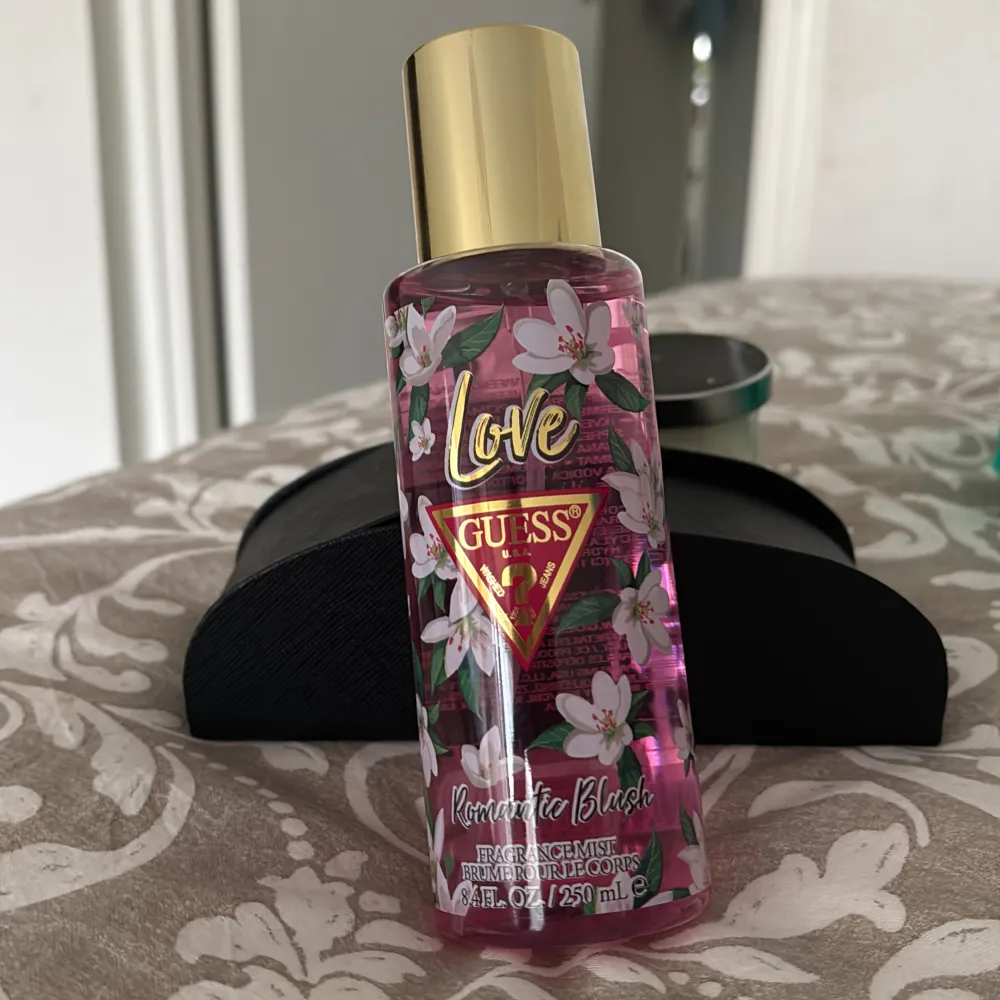 Fräsch och blommig doftspray från Guess, Romantic Blush. Flaskan är dekorerad med vita blommor och har en gyllene kork. Innehåller 250 ml av en lätt och romantisk doft som passar perfekt för daglig användning.. Perfume.
